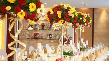 A long banquet table set for a formal event, with floral centerpieces and a well-organized table layout.