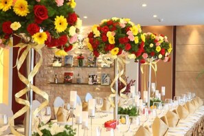 A long banquet table set for a formal event, with floral centerpieces and a well-organized table layout. - Berlin Jianguo International Hotel (Zhumadian)