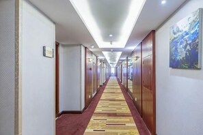 Un pasillo de hotel con puertas de madera, una alfombra estampada y un cuadro en la pared.