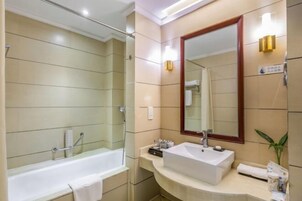 Un baño moderno con bañera, lavabo y un espejo grande.