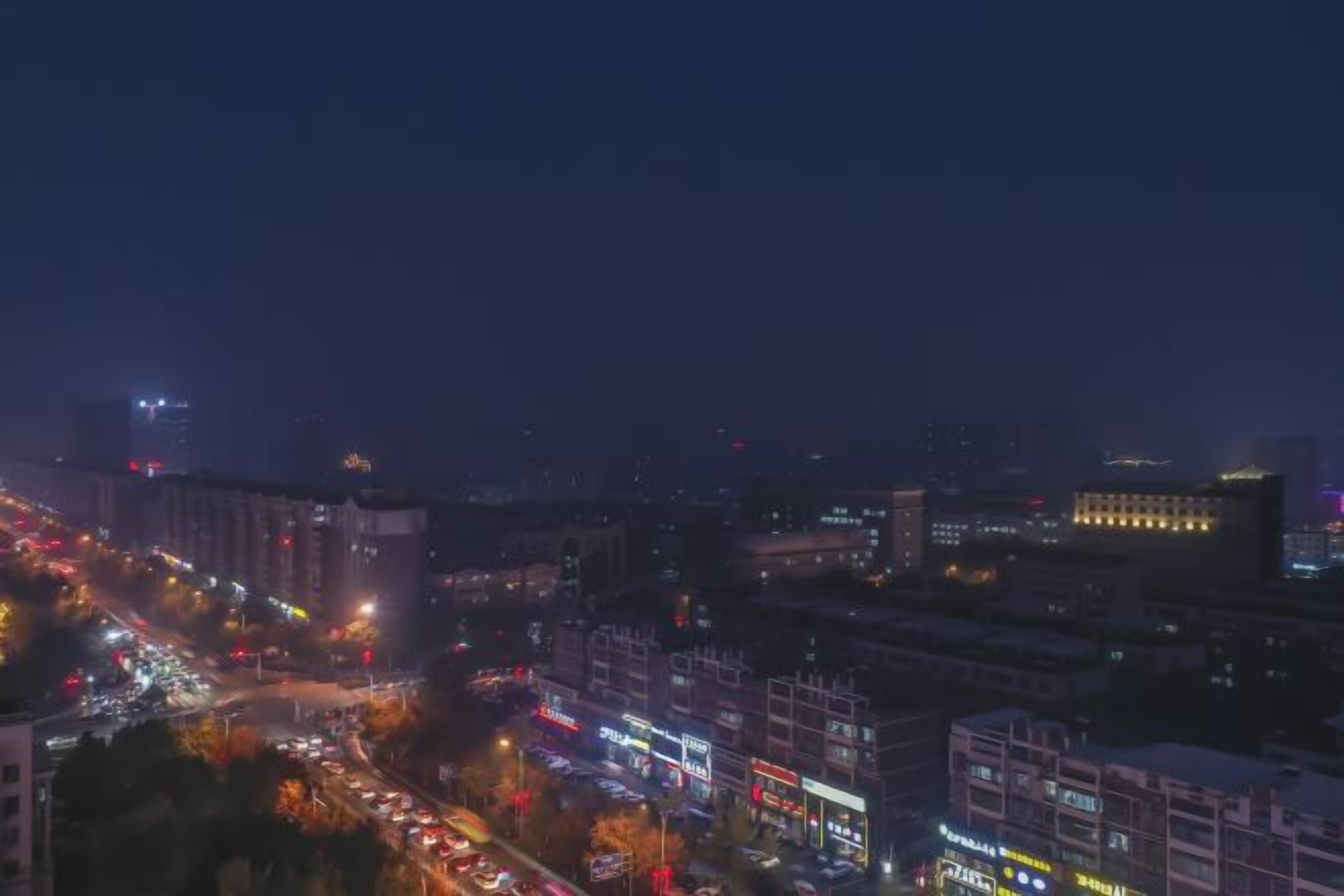 A nighttime cityscape with illuminated buildings and a busy street.