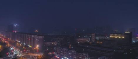 A nighttime cityscape with illuminated buildings and a busy street.