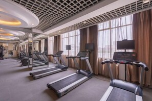 A gym with treadmills, exercise equipment, and large windows with curtains. - Berlin Jianguo International Hotel (Zhumadian)