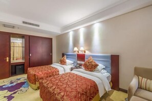 Habitación de hotel con dos camas, un sofá, un escritorio y un armario.