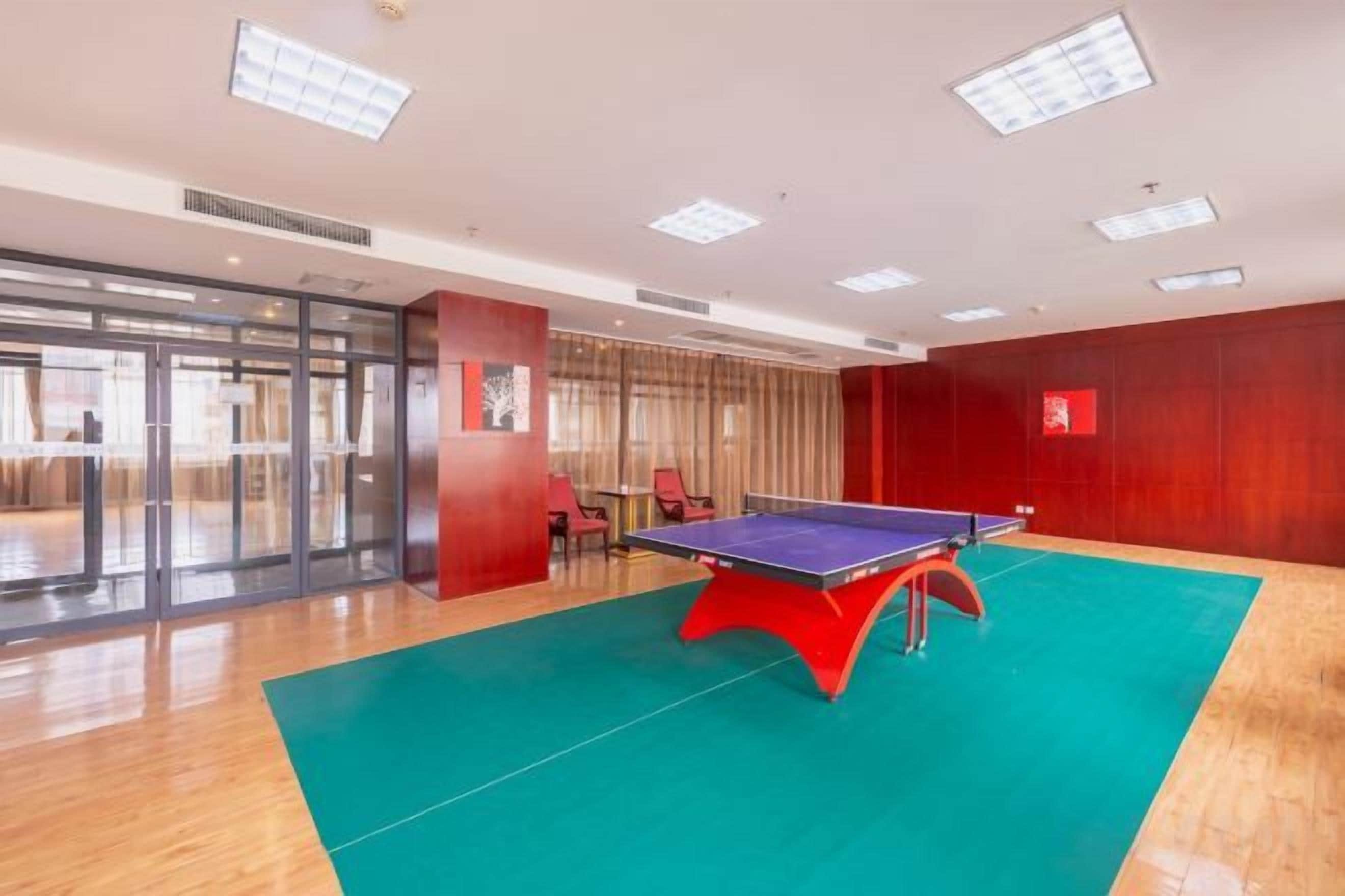 A room with a ping pong table, a green carpet, and a red wall.