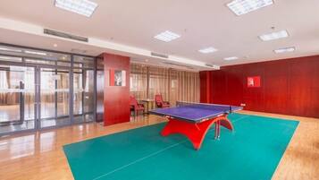 A room with a ping pong table, a green carpet, and a red wall.