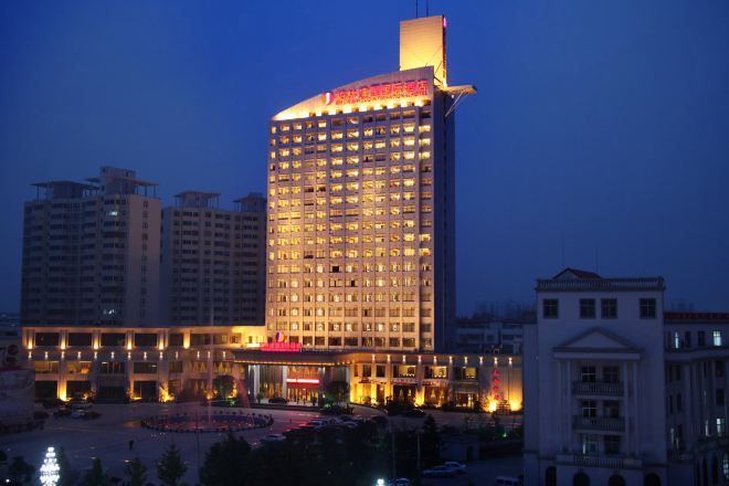 A multi-story hotel with a prominent sign at the top, surrounded by other buildings.