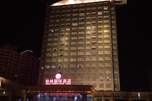 Un edificio de hotel alto con señalización iluminada en la parte superior.