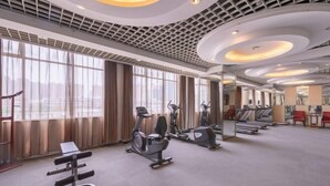 Un gimnasio amplio con máquinas de cardio, una banca y un muro de espejos.