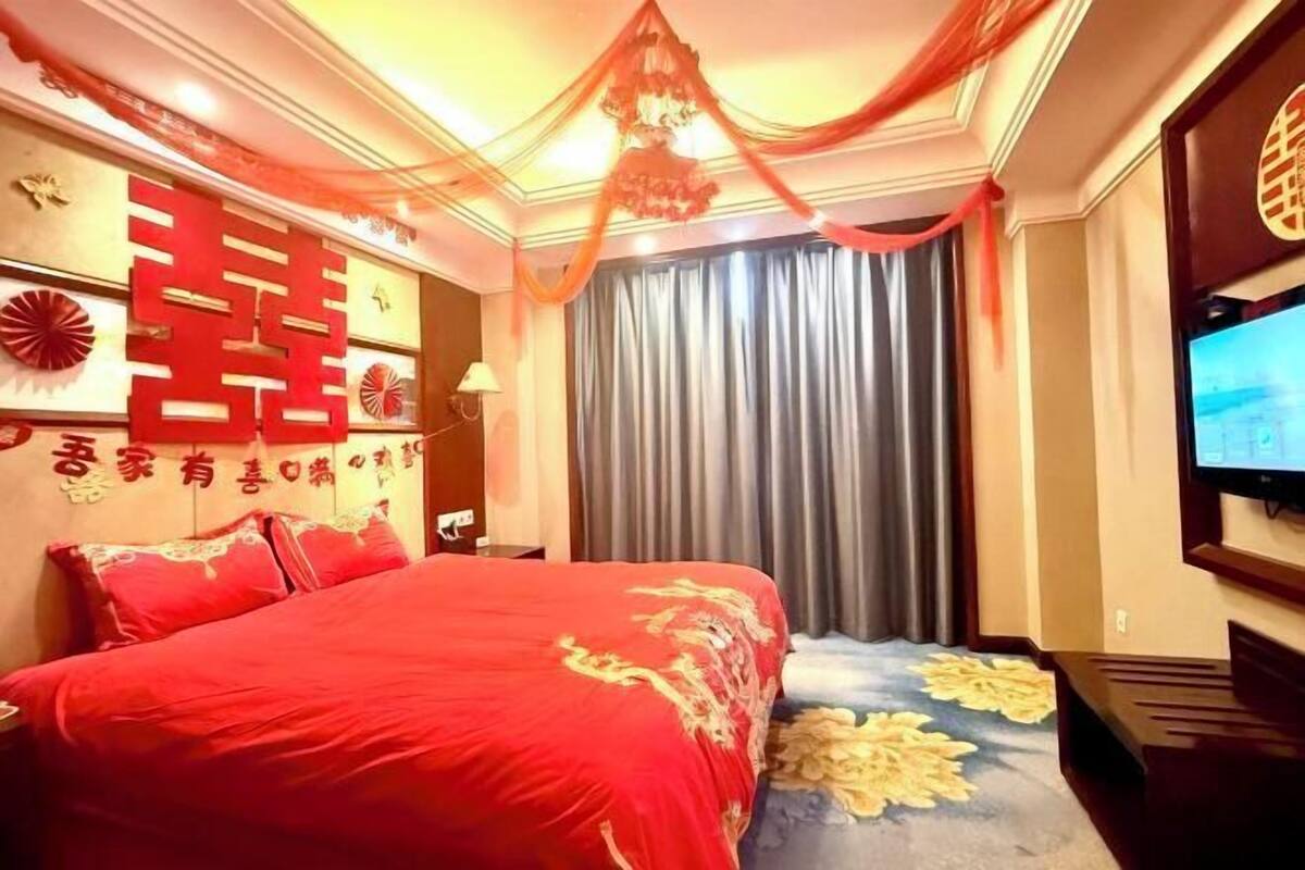Una habitación de hotel con una cama grande, televisión y cortina.