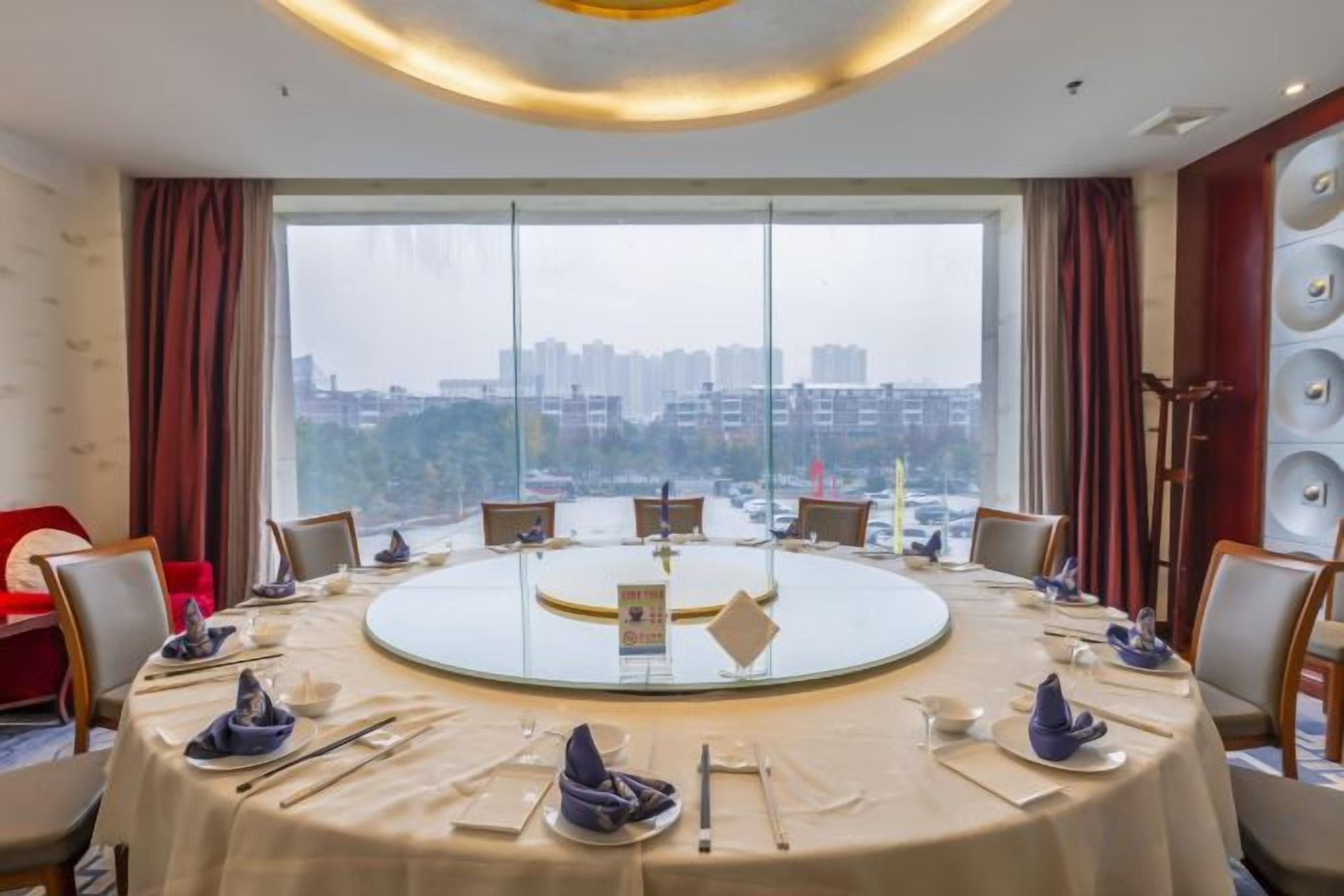 A conference room with a round table, chairs, and a city view through large windows.