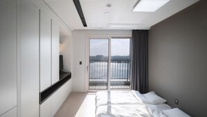 Et moderne hotelværelse med en stor seng, fjernsyn og en balkon med udsigt over vandet.