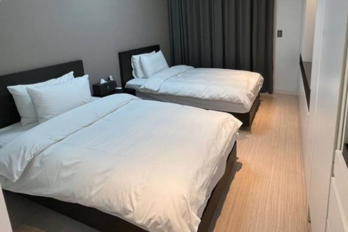 Two single beds with white linens in a hotel room.