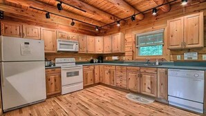 A kitchen with wooden cabinets, a refrigerator, a microwave, an oven, and a dishwasher. - Spacious 8-Bedroom Retreat at Martinwoods Cabins, Perfect for family gatherings (Rockbridge)