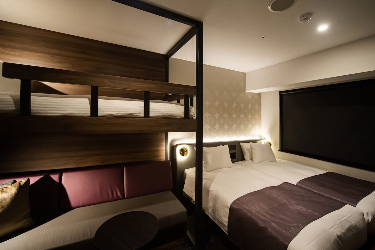 A hotel room with a bunk bed, a sofa, and a large bed.