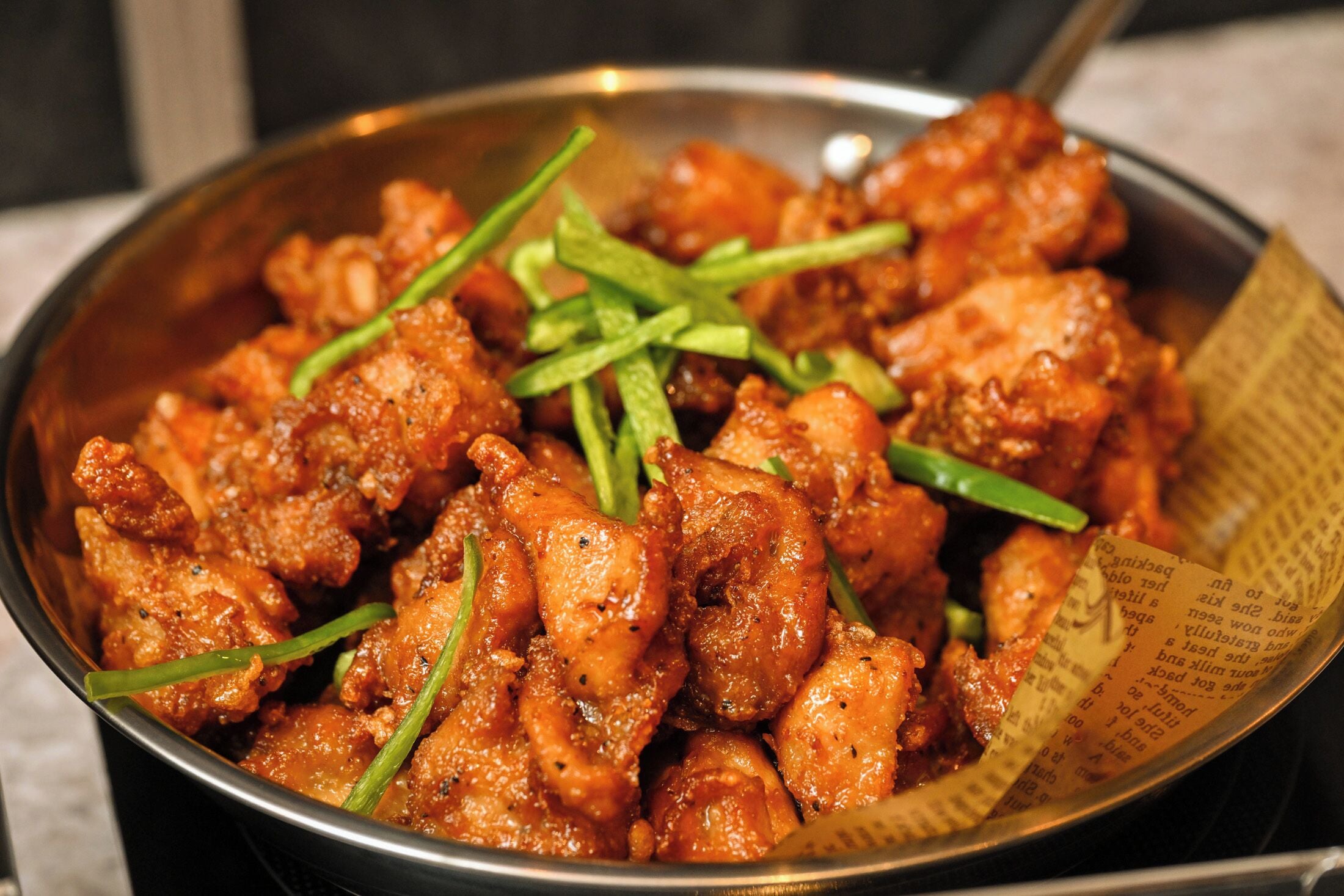 Un bol de poulet frit garni d’oignons verts.