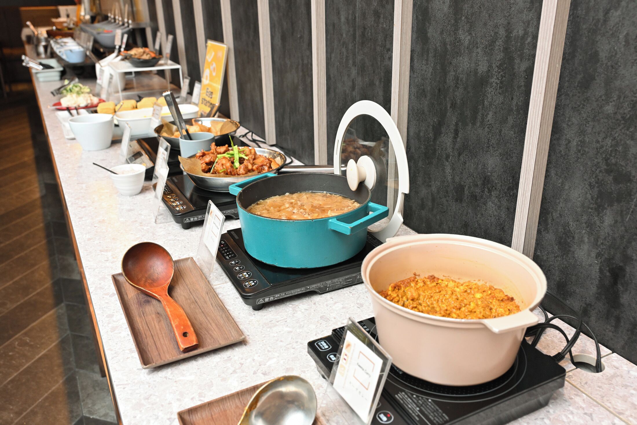 A buffet setup with various dishes and cooking equipment.