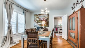 A dining area with a wooden table and chairs, a chandelier, and a large abstract painting on the wall. - Cultural district bungalow steps from Dickies arena (Fort Worth)