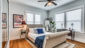 A bedroom with a bed, a nightstand, a dresser, a ceiling fan, and a window with blinds. - Cultural district bungalow steps from Dickies arena (Fort Worth)