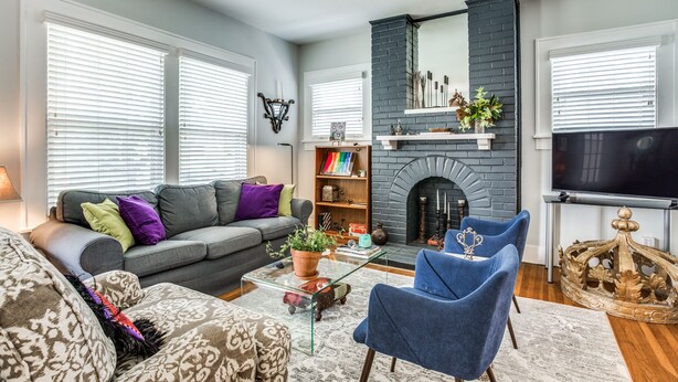 A living room with a grey sofa, blue armchairs, a fireplace, and a television. - Cultural district bungalow steps from Dickies arena (Fort Worth)