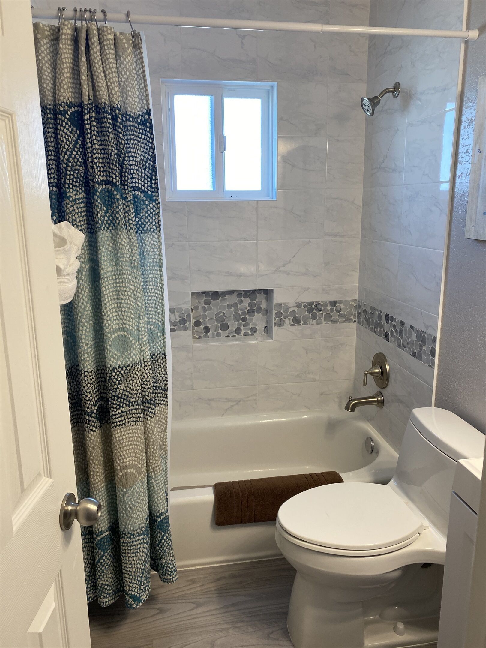 Et badeværelse med badekar, toilet og bruseniche.