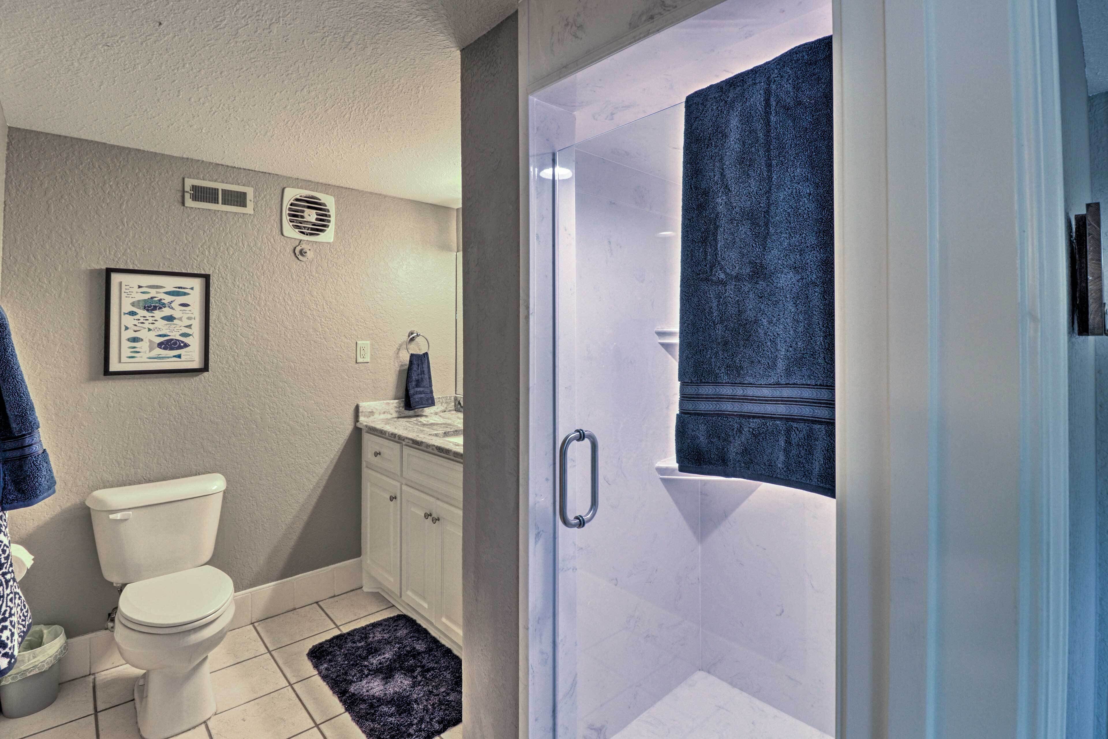 A bathroom with a toilet, a sink, a shower, and a towel rack.