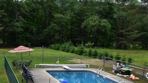 A rectangular pool with a diving board and a slide, surrounded by a fence. - Adirondack Big Pines- House sleeps 12 (Caroga Lake)