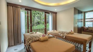 Two single beds with patterned blankets and towels, set against a backdrop of lush greenery and a wooden bench.