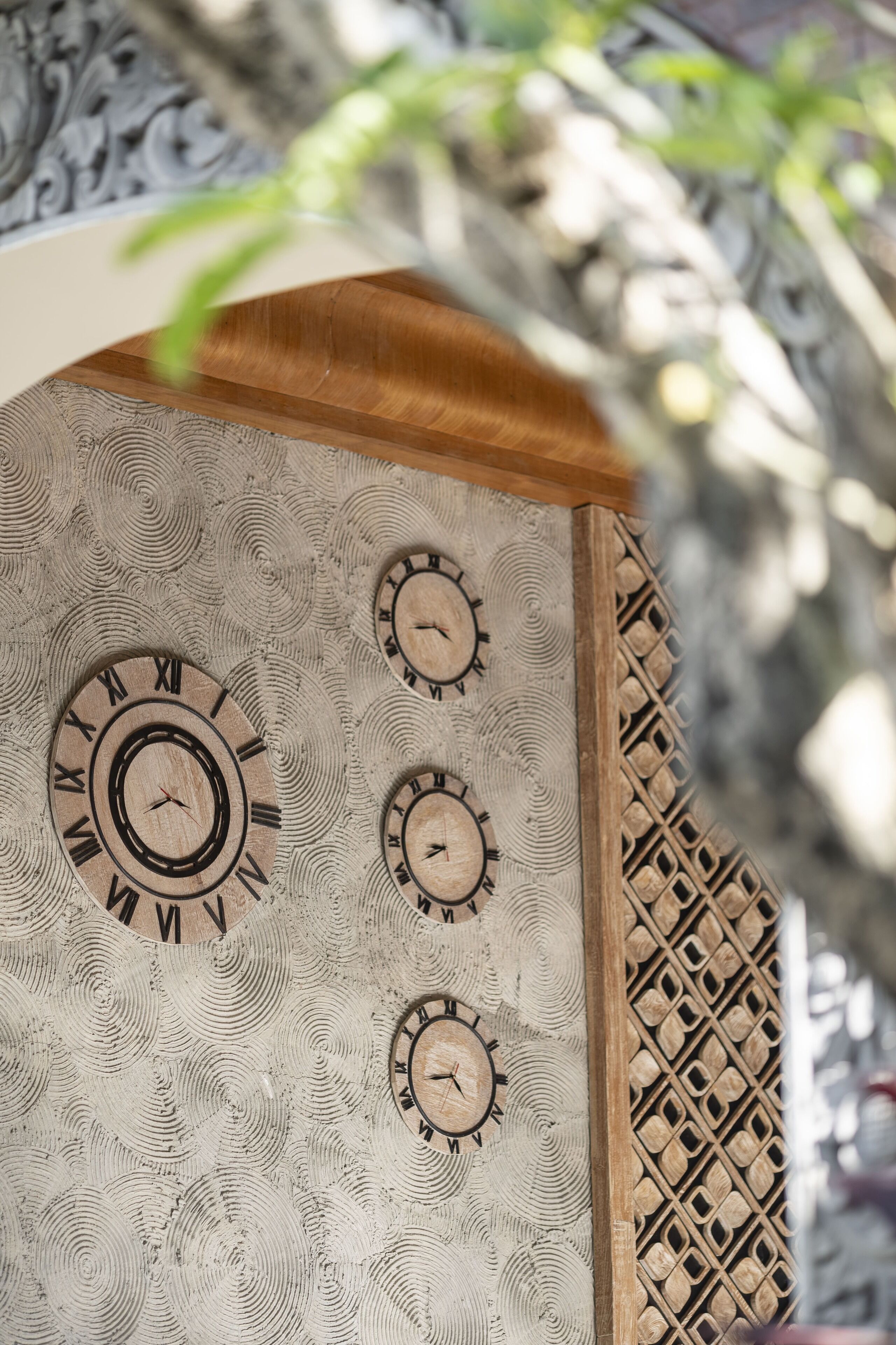 Un muro con diverse pendole incastonate in una superficie strutturata, circondato da una cornice di legno decorativa.
