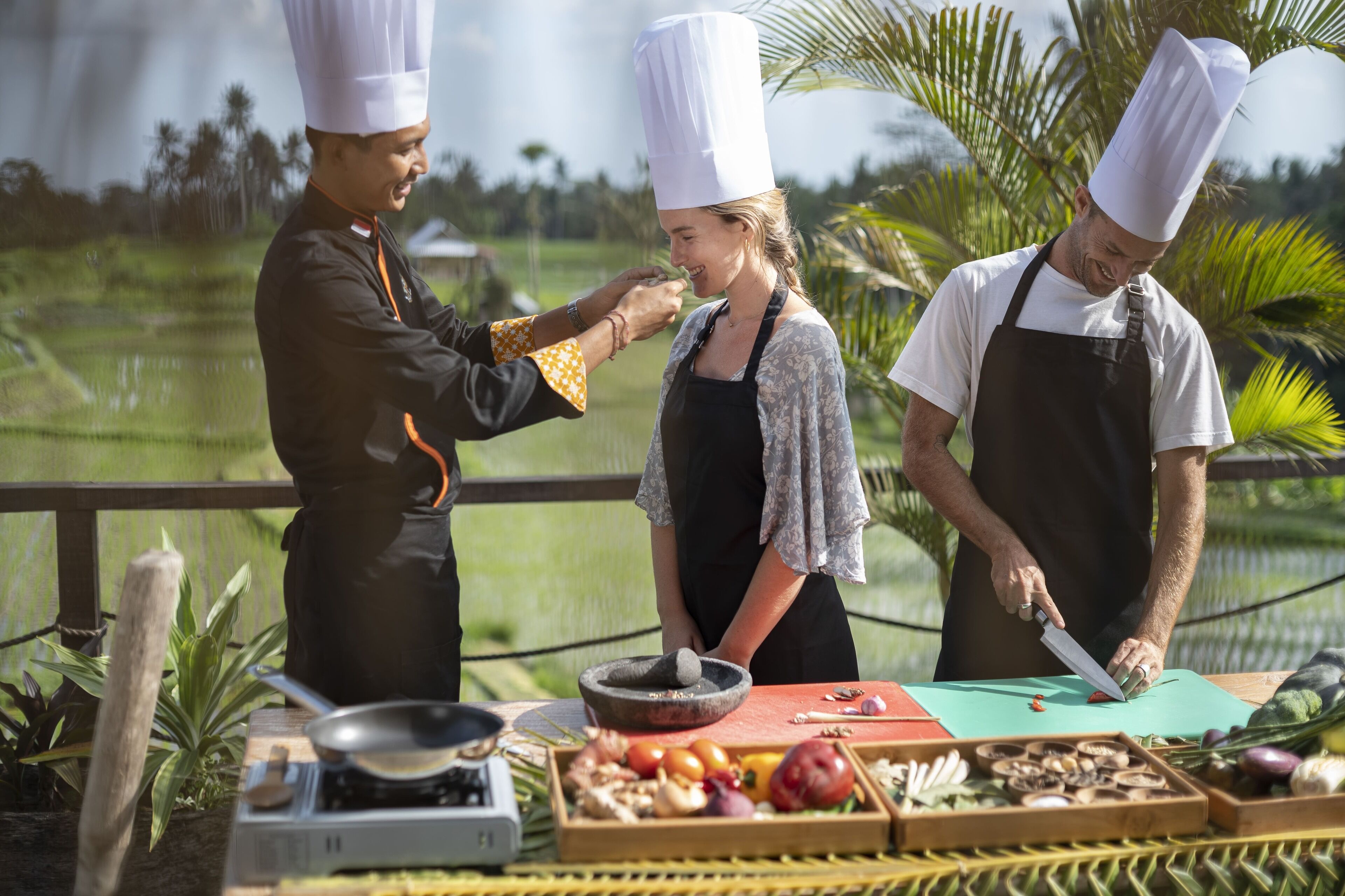 A chef preparing food outdoors with a table full of fresh ingredients.