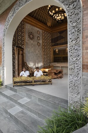 An ornate entrance with a wooden bench, intricate wall carvings, and a patterned ceiling. - The Sun of Granary Resort and Villas (Tegallalang)