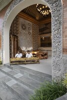 Une entrée richement décorée, avec un banc en bois, des sculptures complexes sur les murs et un plafond orné de motifs.