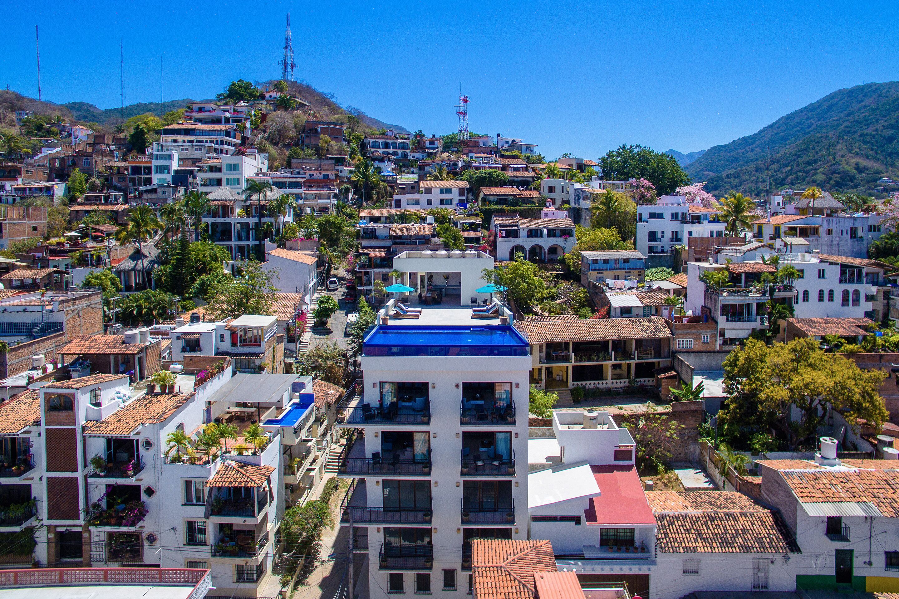 Una zona residencial con construcciones de varios pisos en una ladera pronunciada, algunas con balcones, y un edificio con techo azul que destaca en el centro.