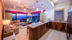 A modern kitchen with a central island, a dining area with a view, and a cozy living space with a sofa and a lamp. - Nise (Puerto Vallarta)