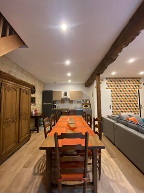 Un espace repas comprenant une longue table en bois, des chaises et un canapé.