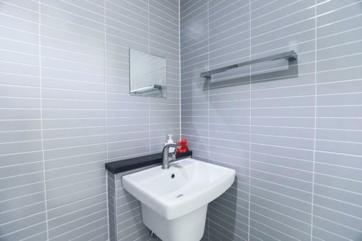 Ein Badezimmer mit einem weißen Waschbecken, einem Spiegel und einer Seifenspender.