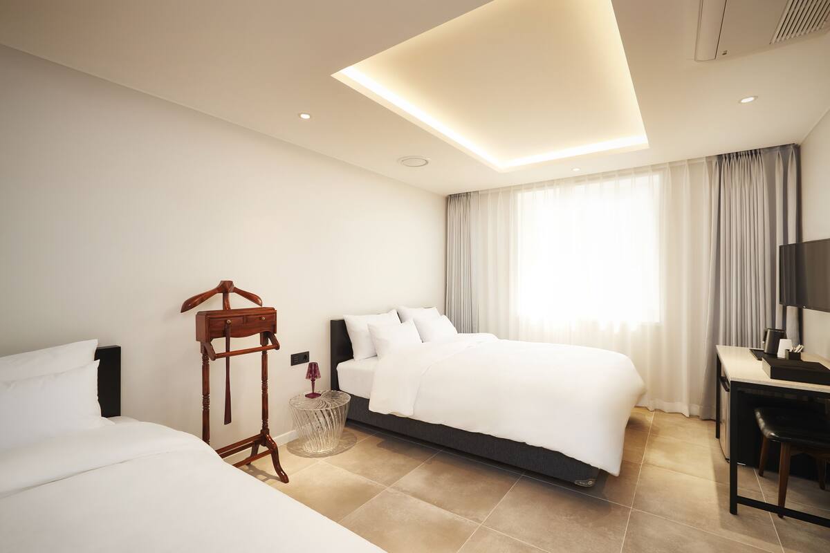 A modern hotel room with a large bed, a desk, and a chair.