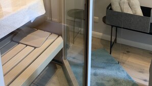 A modern bathroom with a glass shower enclosure, a toilet, a sink, and a towel rack. - Exclusive apartment with private sauna, high-quality kitchen (Zingst)