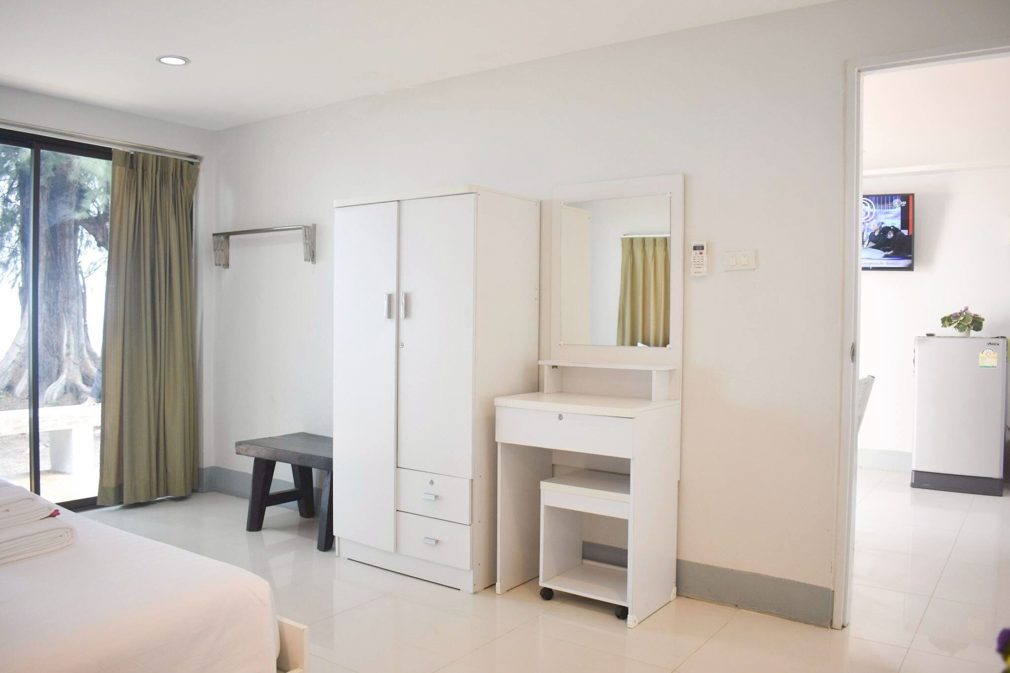 A hotel room with a bed, a desk, a wardrobe, a vanity with a mirror, and a television.