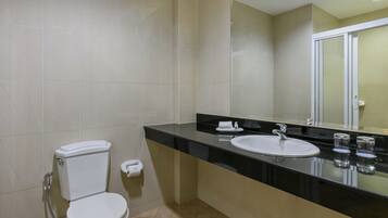 A bathroom with a toilet, sink, and mirror.