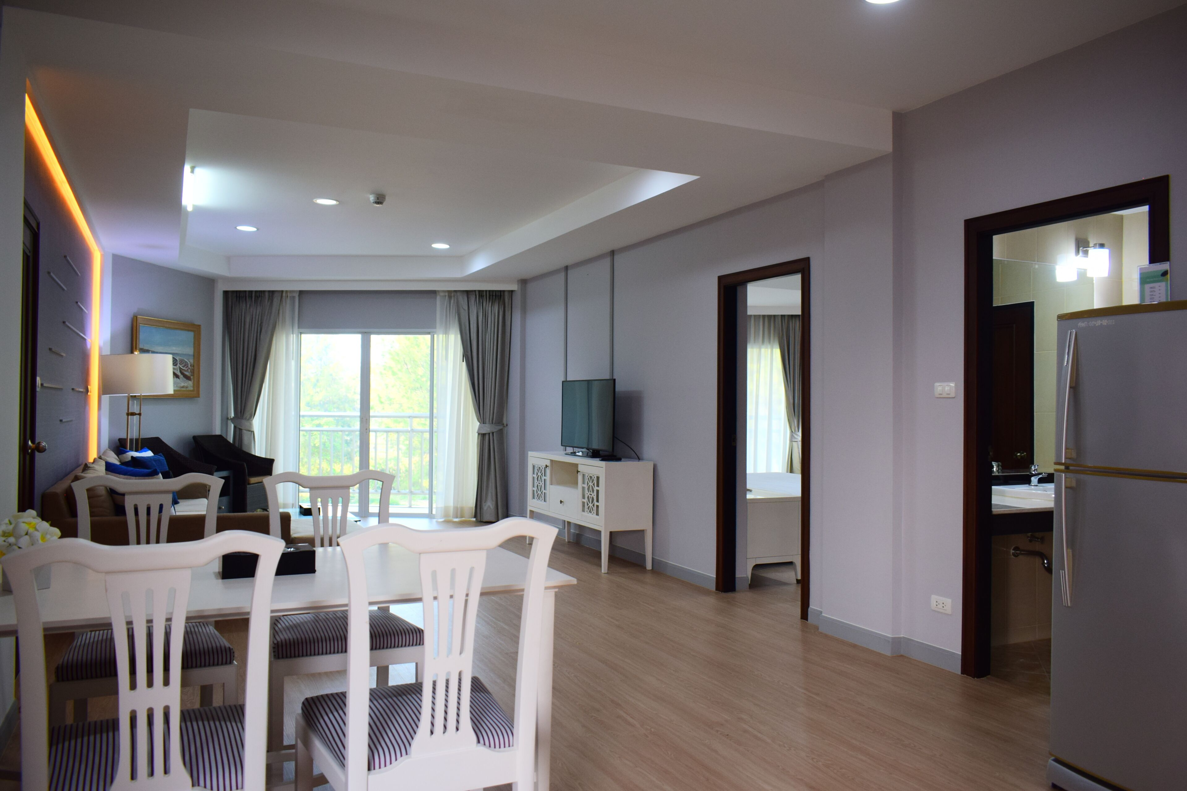 A modern living room with a dining area, a television, and a refrigerator.
