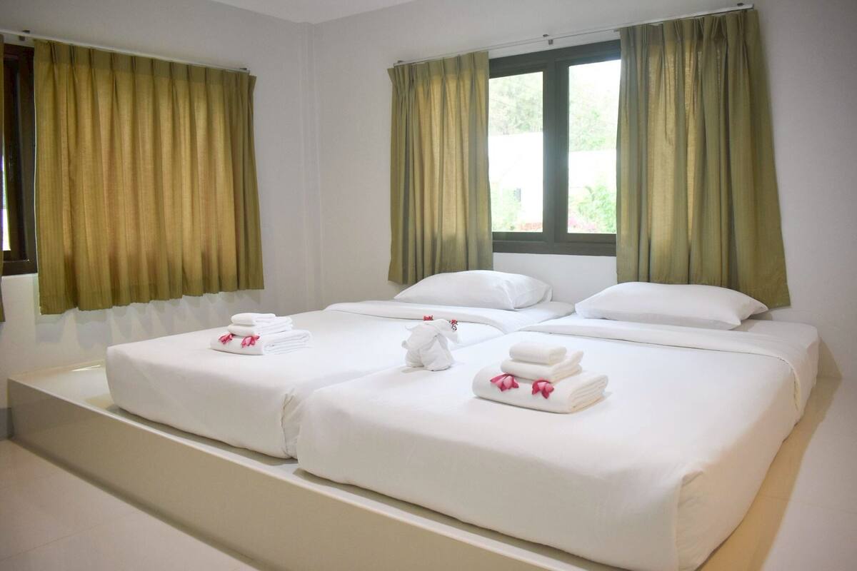 Ett hotellrum med två sängar, gröna gardiner, vita sängkläder och ett fönster med utsikt.