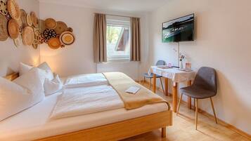 Ein Hotelzimmer mit Bett, Schreibtisch, Stuhl, Fernseher und einer Wand mit gewebten Körben.