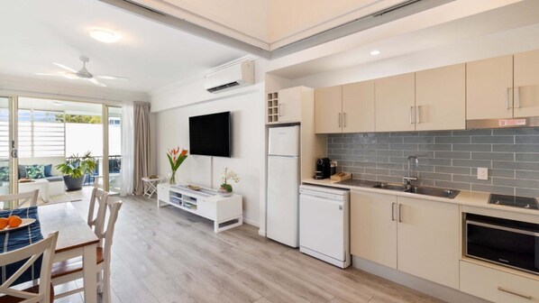 Enjoy meals for two at the dining table, with a flat-screen TV above and a compact kitchen nearby.