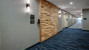 A hotel hallway with a wooden accent wall, a phone, and directional signs.