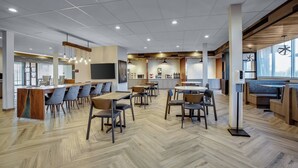 A modern dining area with wooden flooring, multiple tables and chairs, and a bar counter.