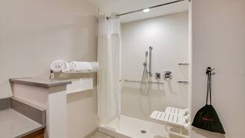 A modern bathroom with a glass-enclosed shower, a white bathtub, and a towel rack with neatly folded towels.
