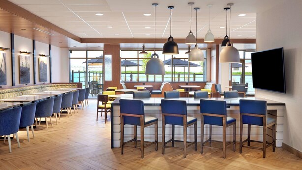 Een moderne eetruimte met een lange balie, blauwe stoelen en hanglampen.