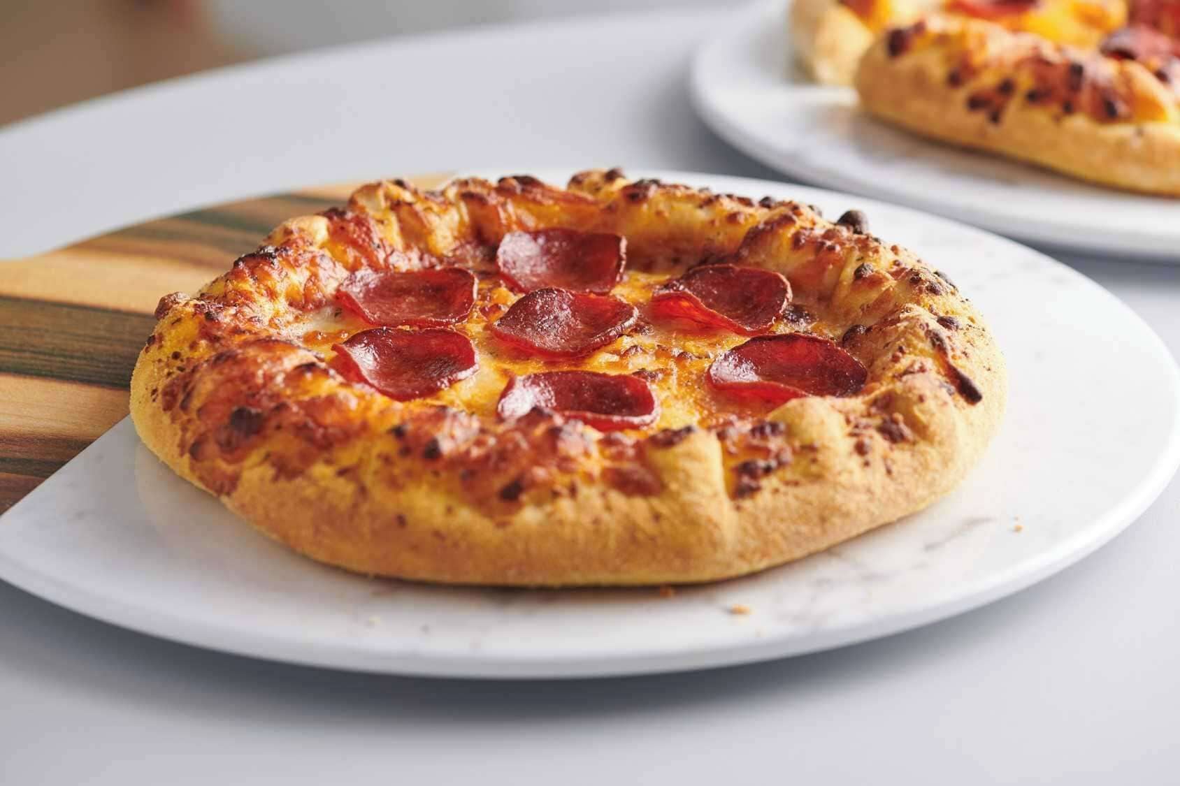 Une pizza à la saucisse piquante, servie sur une assiette blanche.