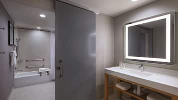 Un baño moderno con un espejo grande, dos lavamanos y zona de ducha.